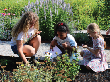 adult and two girls examining flowers